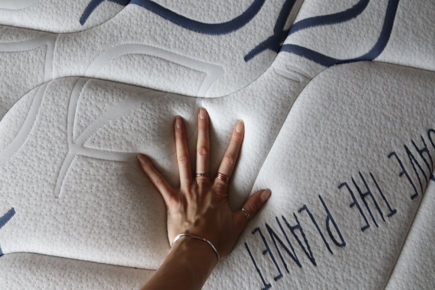 Pessoa a pressionar colchão com a mão